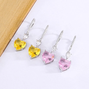 Detailed view of heart-shaped earrings with pink and yellow gemstones on white background
