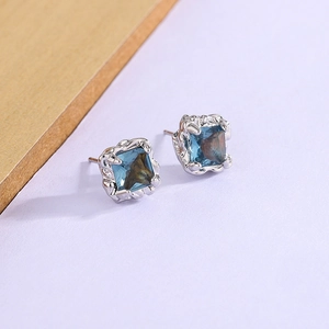 Détail de boucles d'oreilles saphir bleu carré dans une monture vintage blanc argent