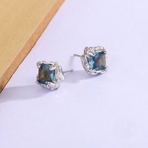 Gros plan de boucles d'oreilles argentées avec cristal bleu et serti à griffes