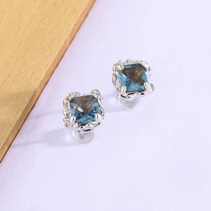 Détail de boucles d'oreilles gemme bleue carrée avec cadre en métal argenté irrégulier