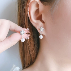 Close-up of elegant flower stud earrings with small diamonds and white hanging pearls