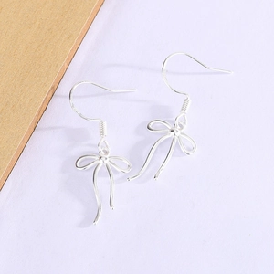 Macro detail of S925 sterling silver bow knot ribbon earrings on a soft purple background