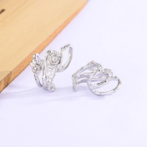 Macro detail of silver rose thorn ear cuffs with vintage floral texture on white background