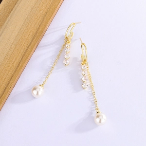 Detail view of long gold tassel earrings with zircon stones and elegant white drop pearls