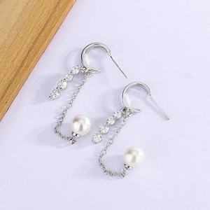 Detailed shot of long tassel earrings with shimmering zircons and elegant white pearls