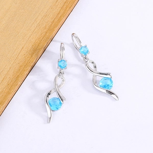 Silver wavy drop earrings featuring blue round gemstones in a sleek ribbon design