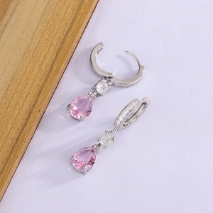 Detail of silver drop earrings featuring pear-cut pink gemstones and micro-pave crystals