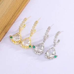 Detail view of gold and silver drop earrings with pear-cut zircon and twisted metal craft