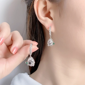 Close-up of pear-shaped zircon drop earring with green stone detail on female model