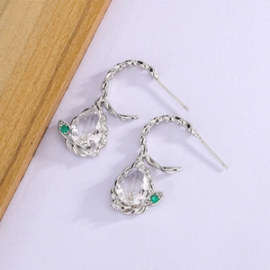 Detail of silver drop earrings with pear-cut clear zircon and green stone accents