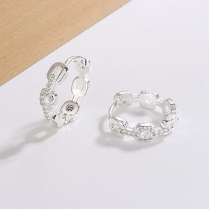 Macro detail of geometric chain hoop earrings with sparkling cubic zirconia on white surface