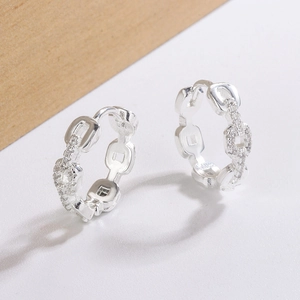 Silver geometric chain earrings with sparkling cubic zirconia on a minimalist wood base