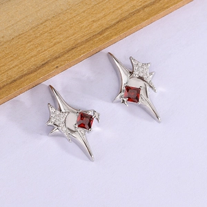 Macro detail of silver star stud earrings with red square zircon and white tiny crystals