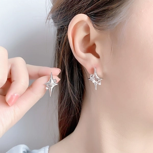Elegant silver star earrings with delicate central pearls worn on model earlobe