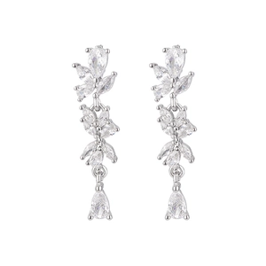 Détail macro de boucles d'oreilles argentées avec cristaux marquise et poire sur fond blanc