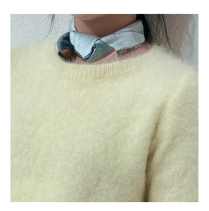 Close-up of a printed silk neck scarf paired with a soft yellow fuzzy mohair sweater