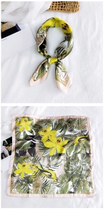 Close-up of tropical floral silk scarf with yellow flowers, birds and green palm leaves