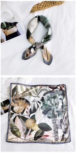 Detailed view of square silk scarf featuring botanical tropical prints and soft fabric texture
