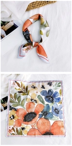 Detailed close-up of floral square silk scarf with watercolor petals and red hem finish