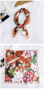 Close-up of printed silk scarf with fox and pink floral pattern on a soft background