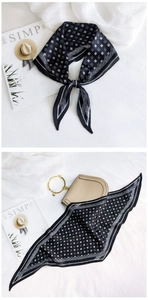 Detail of black and white geometric silk scarf tied on a beige ring handle handbag
