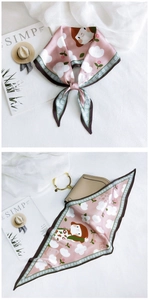 Detail of pink silk scarf featuring cartoon girl and white floral print with beige handbag