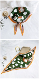 Detail of green diamond scarf with floral and cartoon print and orange edges