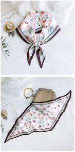 Detail of silk-like scarf with pink flowers and lamb print tied on a stylish leather bag