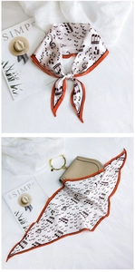Detail of music note silk scarf with orange borders tied on a stylish beige handbag