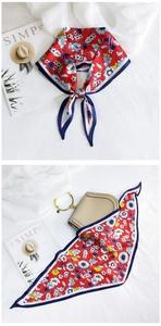 Detail of red floral silk scarf with blue border and elegant gold ring handle bag