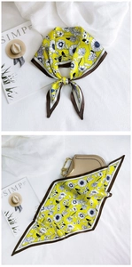 Detail of yellow floral silk scarf tied elegantly and styled on a beige handbag