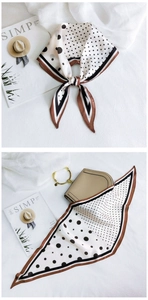 Close-up of a polka dot silk scarf with brown border tied elegantly on a handbag
