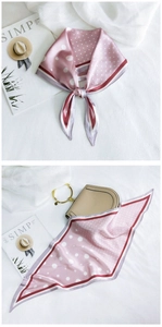 Detail of pink polka dot silk scarf tied on a handbag with chic lifestyle props