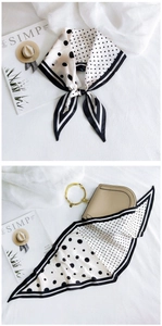 Close-up of elegant black and white polka dot silk scarf tied on a stylish handbag