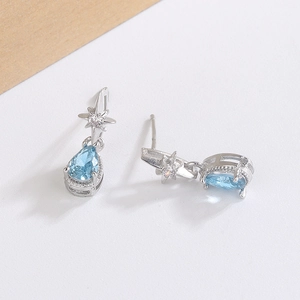 Detail of silver waterdrop earrings featuring blue zircon and starburst motif design