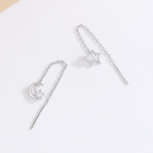 Detailed close-up of asymmetric star and moon tassel earrings with sparkling zircon