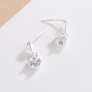 Detail of silver stud earrings featuring round cubic zirconia in a four-prong setting