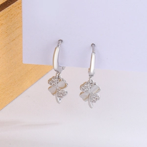 Vue détaillée de boucles d'oreilles trèfle argenté avec nacre blanche et cristaux brillants