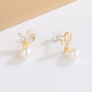 Detailed macro of gold butterfly earrings with marquise crystals and round white pearls