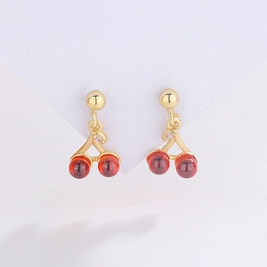 Macro view of cherry earrings with deep red beads and a small sparkling crystal leaf