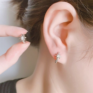 Macro shot showing elegant starburst stud earrings with brilliant zircon on earlobe