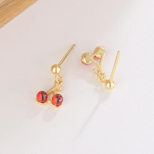 Macro view of gold cherry earrings featuring red resin balls and tiny crystal accents