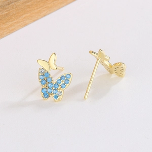 Détail de clous d'oreilles papillon en argent S925 avec pierres bleues et plaqué or