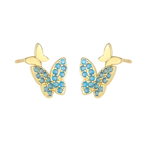 Gros plan de boucles d'oreilles papillon dorées avec ailes en pierres bleues sur blanc