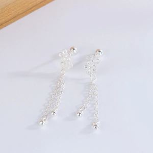 Detail of silver hollow flower stud earrings with long chain tassels and small round beads