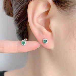 Macro view of hexagonal emerald zircon stud earring with sparkling white stone halo