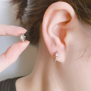 Elegant silver eight-point star hoop earrings with round zircon stones on female model