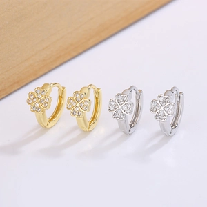 Macro detail of gold and silver four-leaf clover hoop earrings with zircon pavé setting