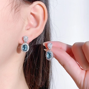 Dettaglio di orecchini a goccia con zircone blu e incastonatura halo in argento S925