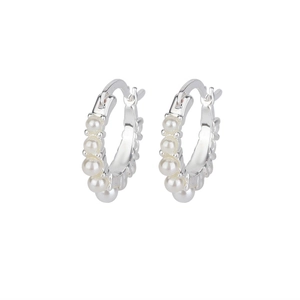 Detail of silver huggie hoop earrings featuring five small white pearls on white background